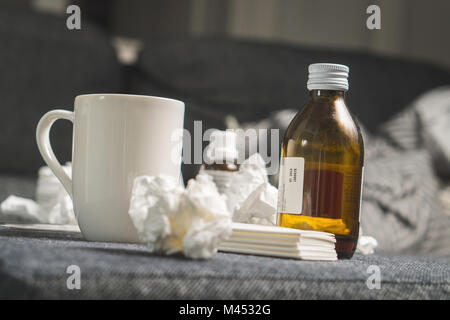 Le rhume, toux sirop, boisson chaude, serviettes en papier et tissus pour battre la maladie, de la fièvre ou de la grippe. Get well kit sur table ou d'un canapé-lit. D'être malade. Banque D'Images