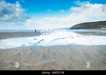 Une figure de marcher sur une plage déserte Rolvenden Cornwall UK. Banque D'Images