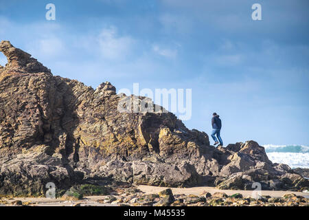 Un homme grimper Chapelle Rocher sur Broad Oak Beach à Cornwall UK. Banque D'Images