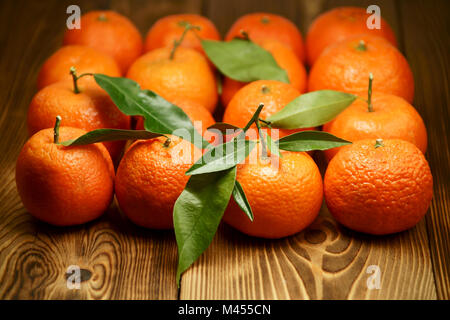 Mandarines avec des feuilles vertes disposées en carré sur les planches de bois Banque D'Images