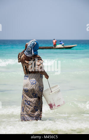 Femme en attente de bateau de pêche pour entrer en shore à Stone Town, Zanzibar, Tanzanie. Banque D'Images