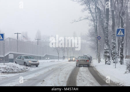 Rue de la ville sous la neige lors d'une forte tempête de neige en hiver. Mauvaise l'enlèvement de la neige. Douche des précipitations. Météo neige. Embouteillage. route glissante et cerise Banque D'Images