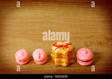 Macarons rose et biscuits de Noël isolé sur fond de bois. Banque D'Images