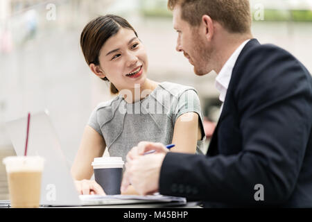 Young businessman and woman having discussion at sidewalk cafe Banque D'Images