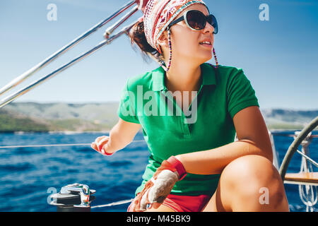 Young woman crouching on yacht près de la côte, Croatie Banque D'Images