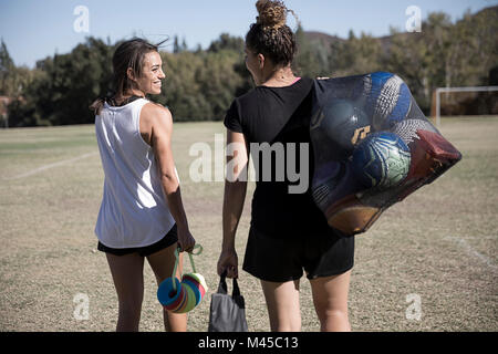 Les femmes sur terrain de football ballons transportant dans sac net Banque D'Images