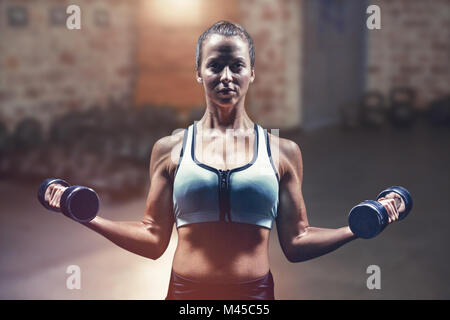 Image composite de young man holding dumbbells Banque D'Images