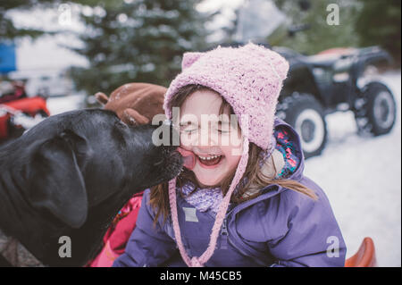 Jeune fille avec chien dans paysage de neige, chien de lécher le visage de fille Banque D'Images