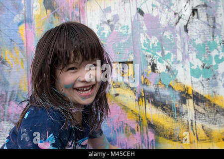 Portrait de jeune fille en mur peint smiling at camera Banque D'Images