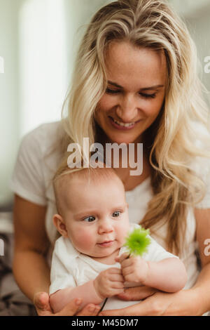 Bébé fille assise sur les genoux de sa mère à la fleur au Banque D'Images