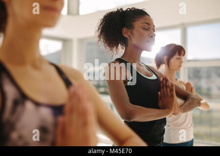 Jeune femme fit pratiquer le yoga avec des amis. Femme Fitness le yoga la méditation à l'intérieur en cours de gymnastique. Banque D'Images
