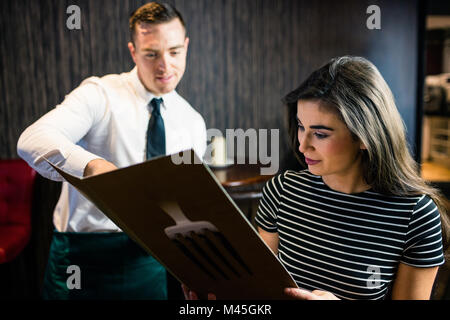 Jolie femme de passer commande pour le serveur dans le menu Banque D'Images