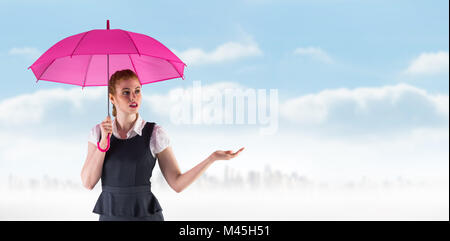 Image composite de pretty redhead businesswoman holding umbrella Banque D'Images