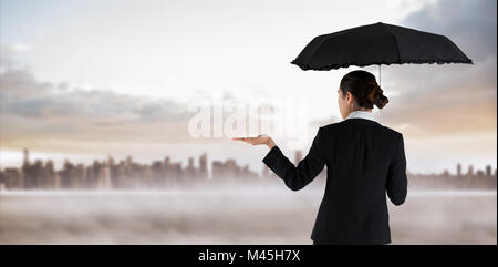 Composite image of young businesswoman holding umbrella Banque D'Images