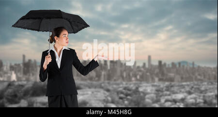 Composite image of young businesswoman holding umbrella Banque D'Images