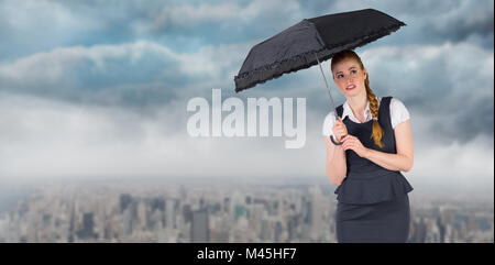 Image composite de pretty redhead businesswoman holding umbrella Banque D'Images