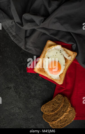 Vue de dessus de l'oeuf au plat sur toast et tranches de pain sur la surface sombre Banque D'Images