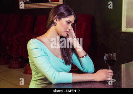 Femme sérieuse ayant le vin rouge au comptoir du bar Banque D'Images