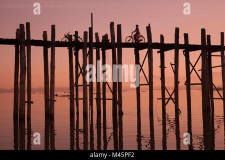 Monk marche à aube sur le lac près de pied en bois U Bein bridge pont traversant le lac Taungthaman près de Amarapura à Mandalay Myanmar Banque D'Images