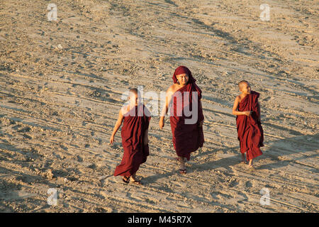 Jeunes moines marcher sur le rivage sablonneux près de U Bein Bridge au Myanmar Banque D'Images
