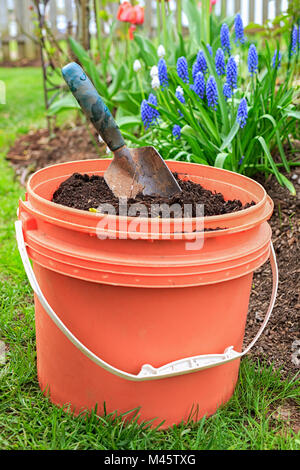 Un seau de compost avec une truelle de jardin dans le jardin. Banque D'Images