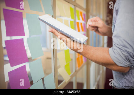 Image composite de businessman using digital tablet over white background Banque D'Images