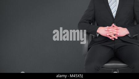 Image composite de stern businessman assis sur une chaise de bureau Banque D'Images