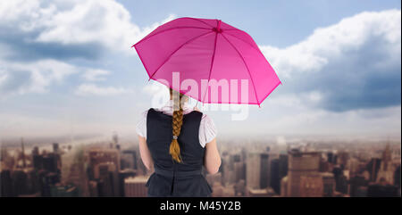 Image composite de pretty redhead businesswoman holding umbrella Banque D'Images