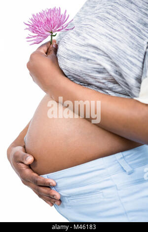 Femme enceinte avec une fleur de toucher son ventre Banque D'Images