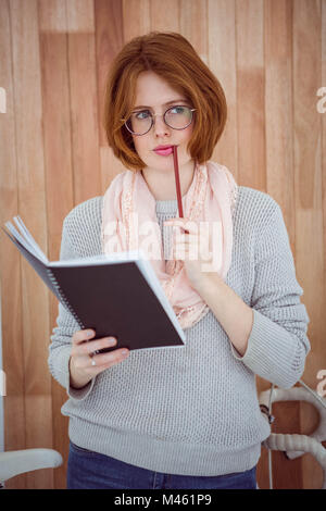 Hipster femme pensive avec un bloc-notes et crayon Banque D'Images