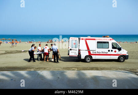 Les paramédics espagnol face à un homme blessé sur la plage de Malaga, Espagne. Banque D'Images