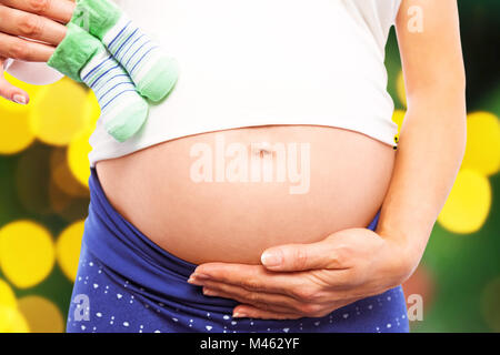 Image composite de pregnant woman holding baby shoes sur bump Banque D'Images