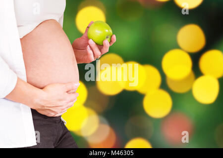 Image composite de midsection of pregnant woman holding green apple Banque D'Images