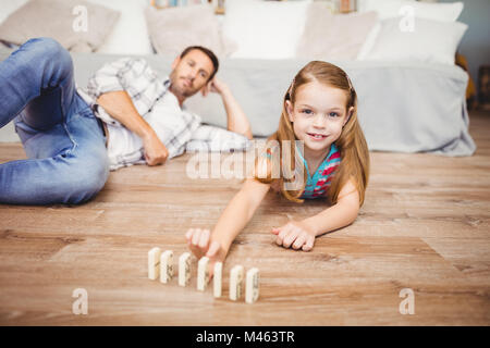 Happy girl organiser par le père domino sur plancher de bois franc Banque D'Images