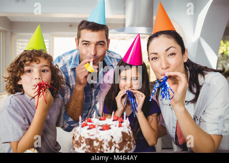 Happy Family blowing party horn lors d'anniversaire Banque D'Images