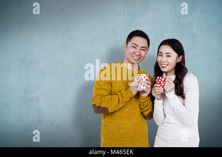 Image composite de portrait of happy young couple holding tasses Banque D'Images