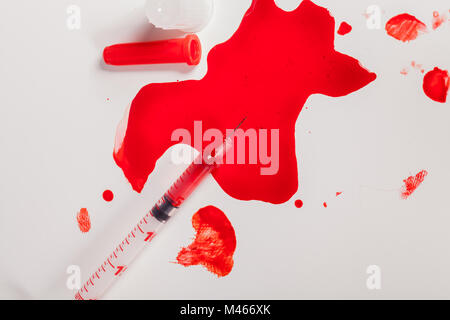 Seringue injectant du sang rouge sur fond blanc Banque D'Images
