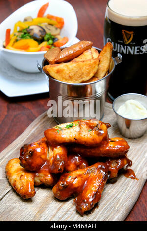 Des ailes de poulet sautées dans barbecue et sauce chili douce servi avec trempette au fromage bleu, frites et une pinte de Guinness, Doheny & Nesbitt Pub, Dublin, Irlande Banque D'Images