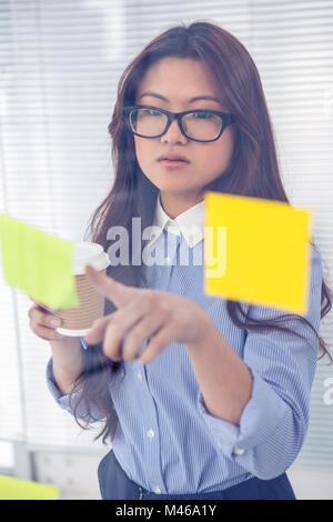 Asian businesswoman en utilisant les notes sur le mur Banque D'Images