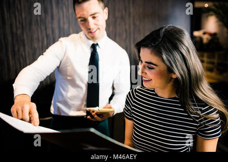 Jolie femme de passer commande pour le serveur dans le menu Banque D'Images