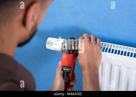 Close-up of a Young male plombier à l'aide d'une clé pour fixer le thermostat Banque D'Images