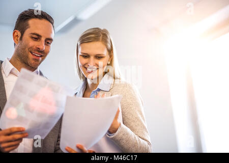 Smiling jeunes gens d'affaires à examiner des documents dans Office Banque D'Images