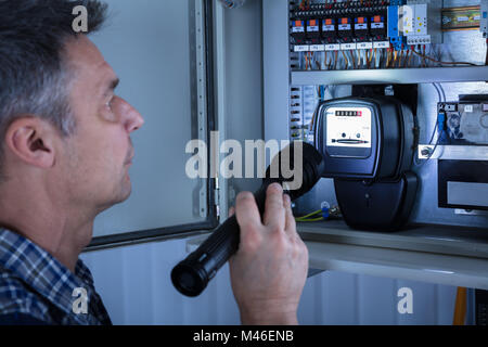 Close-up d'un électricien l'examen d'une boîte à fusibles avec une torche Banque D'Images