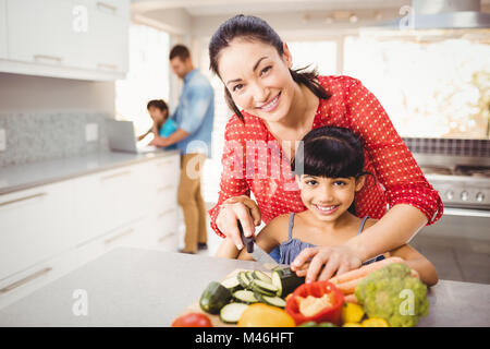 Portrait de l'enseignement de mère heureuse fille pour couper les légumes Banque D'Images