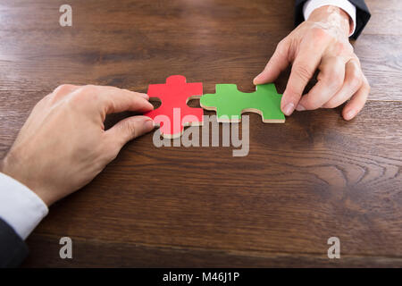 Close-up de deux hommes d'adhérer à des morceaux de puzzle en bois sur 24 Banque D'Images
