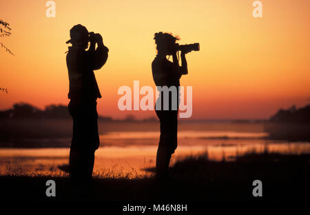 Le Zimbabwe. Près de Victoria Falls. Fleuve Zambèze. Le lever du soleil. Les touristes. Woman taking photo. Photographes Marjolijn van Frans Lemmens et officiel. Banque D'Images
