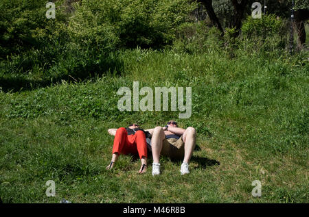 Rome, Italie : un jeune couple repose sur l'herbe au soleil Banque D'Images