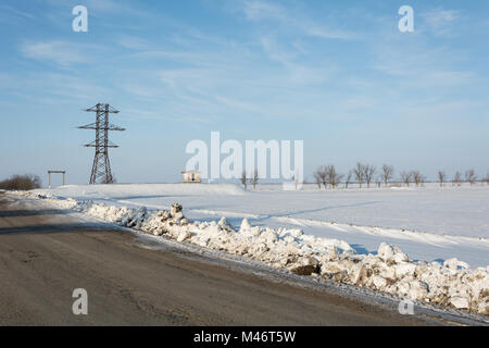 Ligne d'alimentation électrique sur pied la neige en face de ciel bleu et nuages Banque D'Images