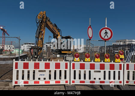 Chargeur sur roues jaune derrière une entrée du site de construction fermée dans le nouveau quartier de Riedberg, Francfort, Allemagne Banque D'Images