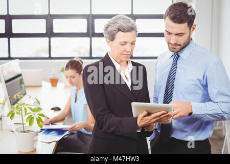 Businesswoman explaining collègue masculin sur tablette numérique Banque D'Images